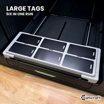 Six large black metal luggage tags filling the outer pockets of the Samcraft xTool Omni jig, six in one run.