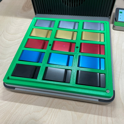 Samcraft green metal money clip jig in an xTool F1 Ultra laser bed, holding a grid of anodised metal money clips in mixed colours.