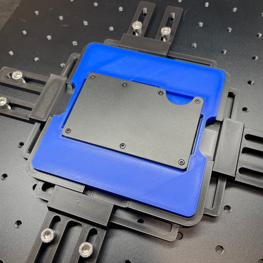 Samcraft blue metal wallet jig on a ComMarker laser bed, showing the recess sized for a metal card wallet.