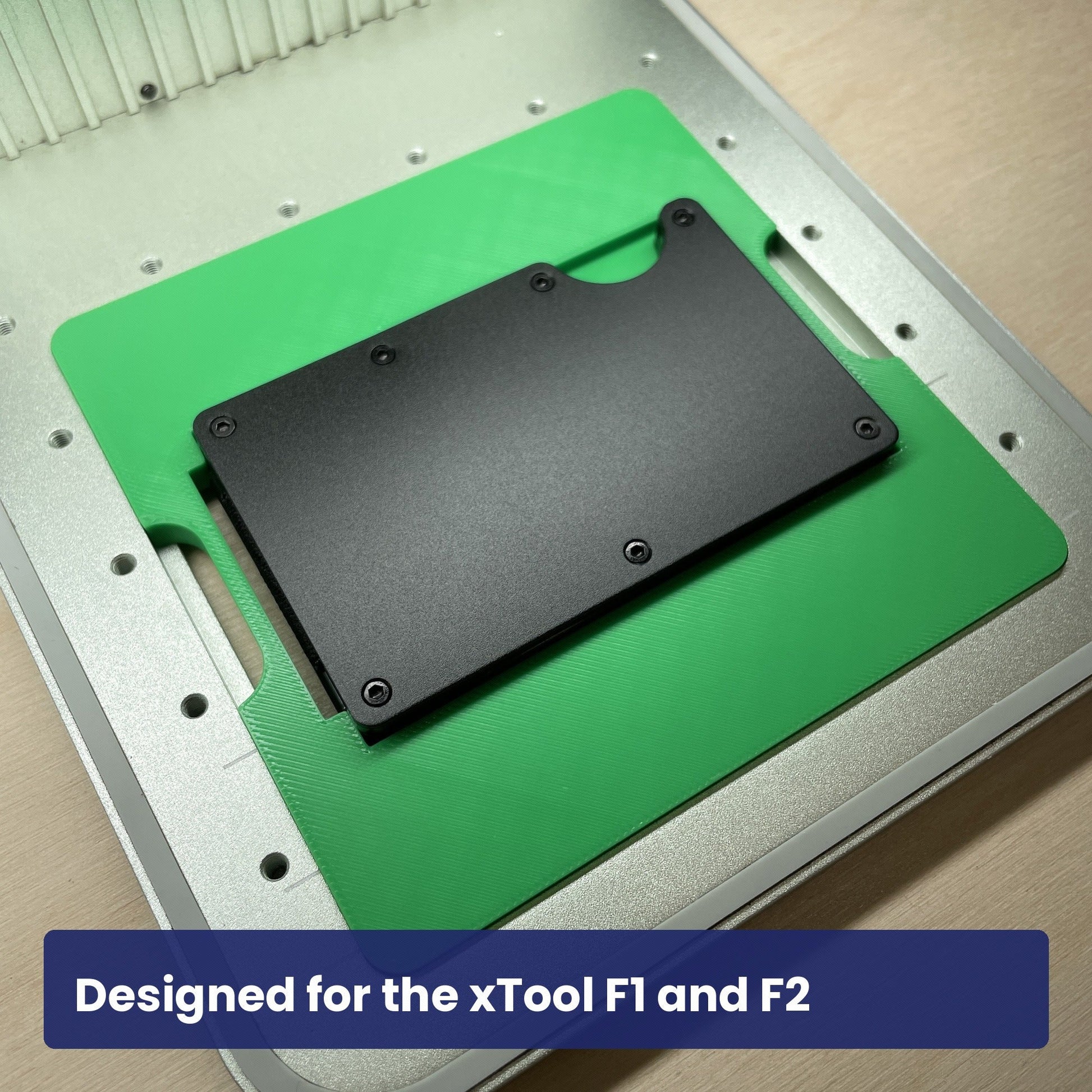 Samcraft metal wallet jig seated in the xTool F1 base plate with a black metal wallet in the recess.