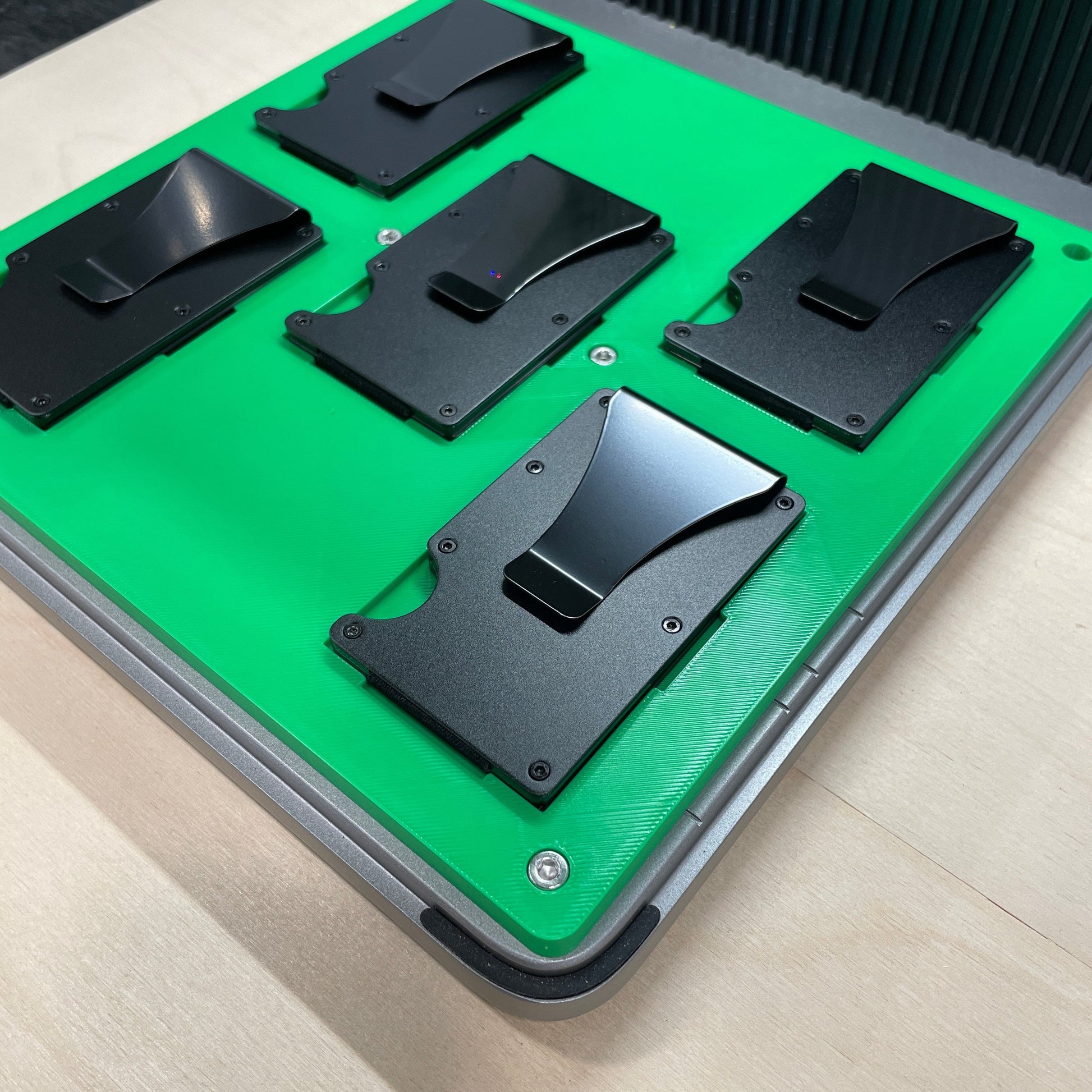 Samcraft green metal wallet jig in an xTool F1 Ultra laser bed, holding black metal card wallets.