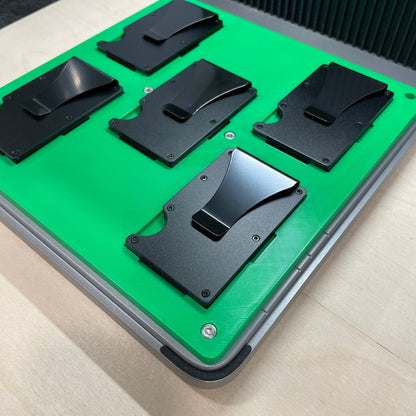 Samcraft green metal wallet jig in an xTool F1 Ultra laser bed, holding black metal card wallets.