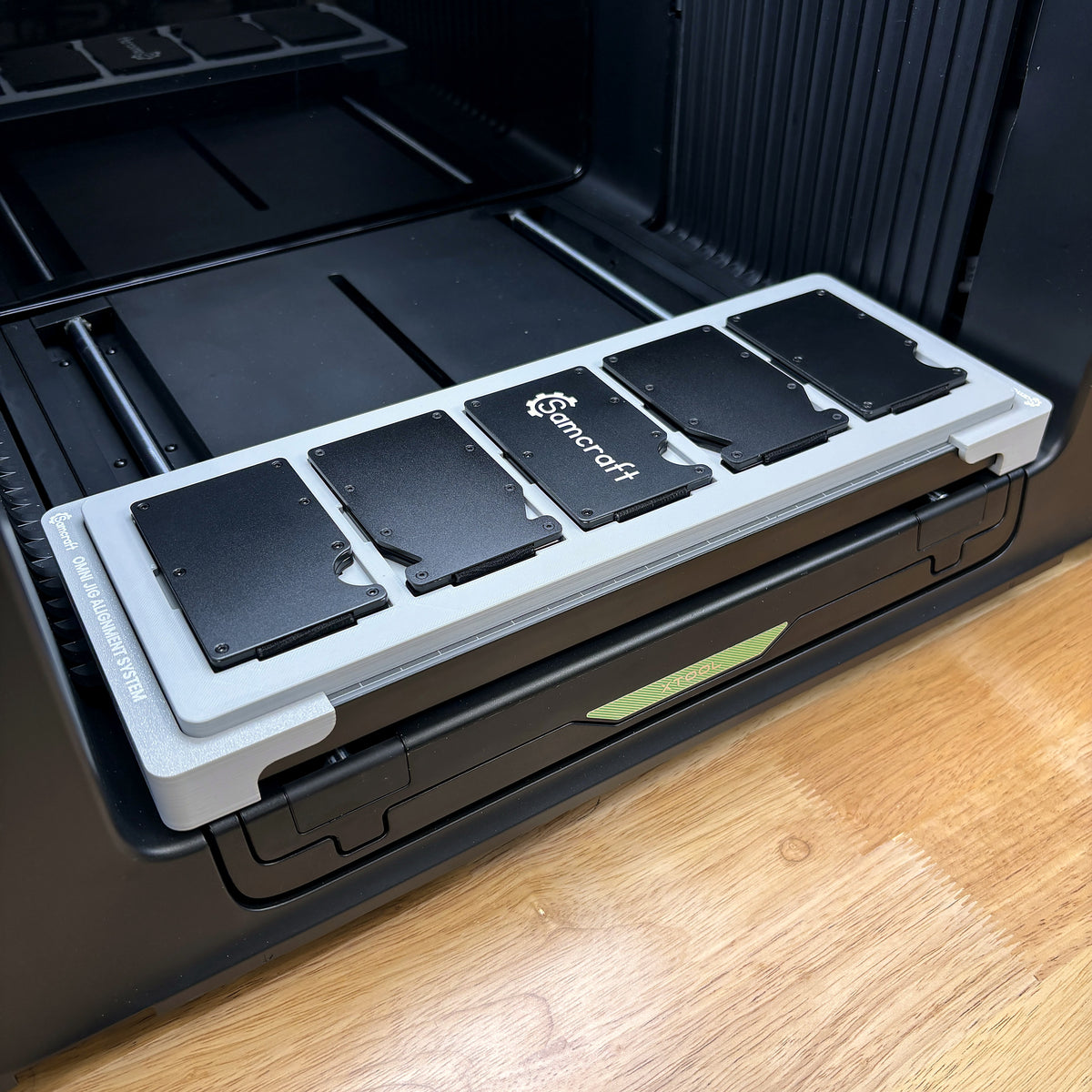 Samcraft metal wallet jig on the bed of an xTool Omni UV printer, holding five metal RFID card holder wallets in a row.