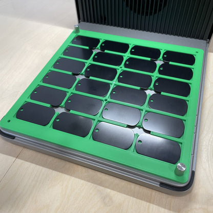 Samcraft green military dog tag jig in an xTool F1 Ultra laser bed, holding a full grid of black dog tags.