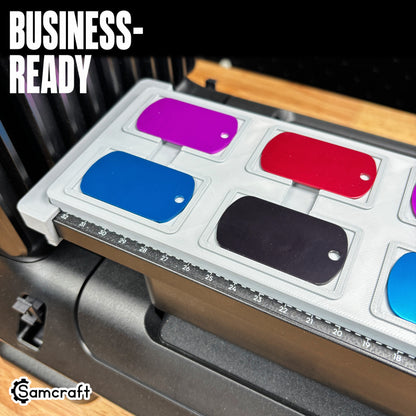 Samcraft Military Dog Tag Jig for eufyMake E1 UV printer, overhead view showing purple, red, blue, and black anodized aluminum dog tags seated in a gray 3D-printed tray with "Business-Ready" text.