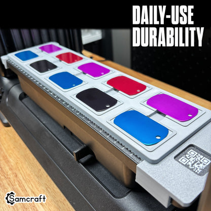 Right-angle perspective of the Samcraft dog tag jig filled with vibrant anodized tags, highlighting daily-use durability on the eufyMake E1 print bed.