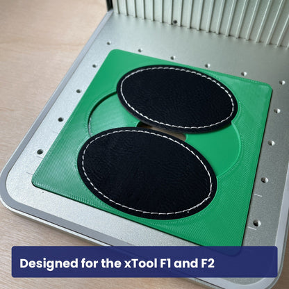 Samcraft oval patch jig in the xTool F1 base plate holding two black leatherette oval patches.