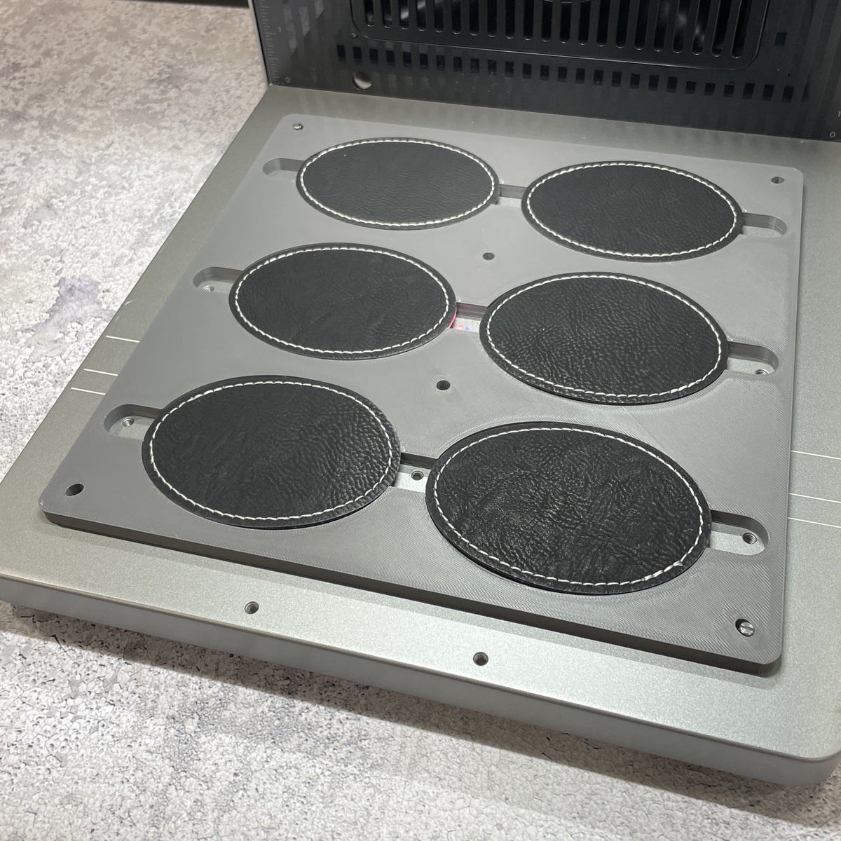 Samcraft oval patch jig on the xTool F2 Ultra bed, holding six dark oval leatherette patches.