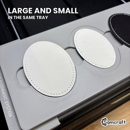 A large and a small leatherette oval patch seated in the same Samcraft xTool Omni jig, showing both sizes run in the same tray.