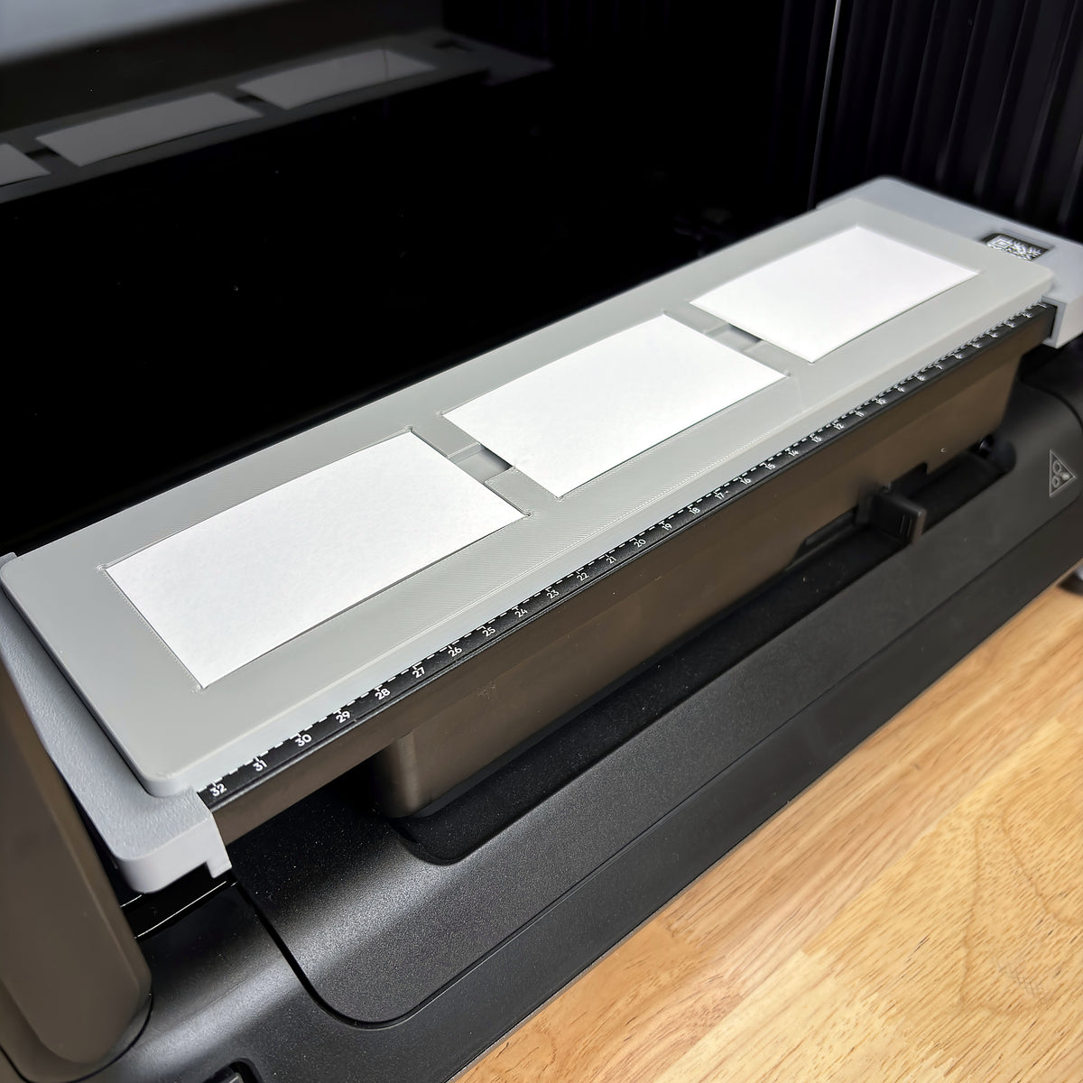 Samcraft paper business card jig on the bed of a eufyMake E1 UV printer, holding three white 3.5 x 2 inch business cards in a row.