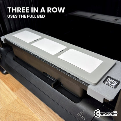 Angled view of the Samcraft eufyMake E1 paper business card jig showing three cards in a single row along the length of the print bed.