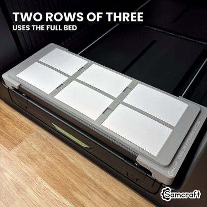 Angled view of the Samcraft xTool Omni paper business card jig showing two rows of three cards across the full width of the bed.