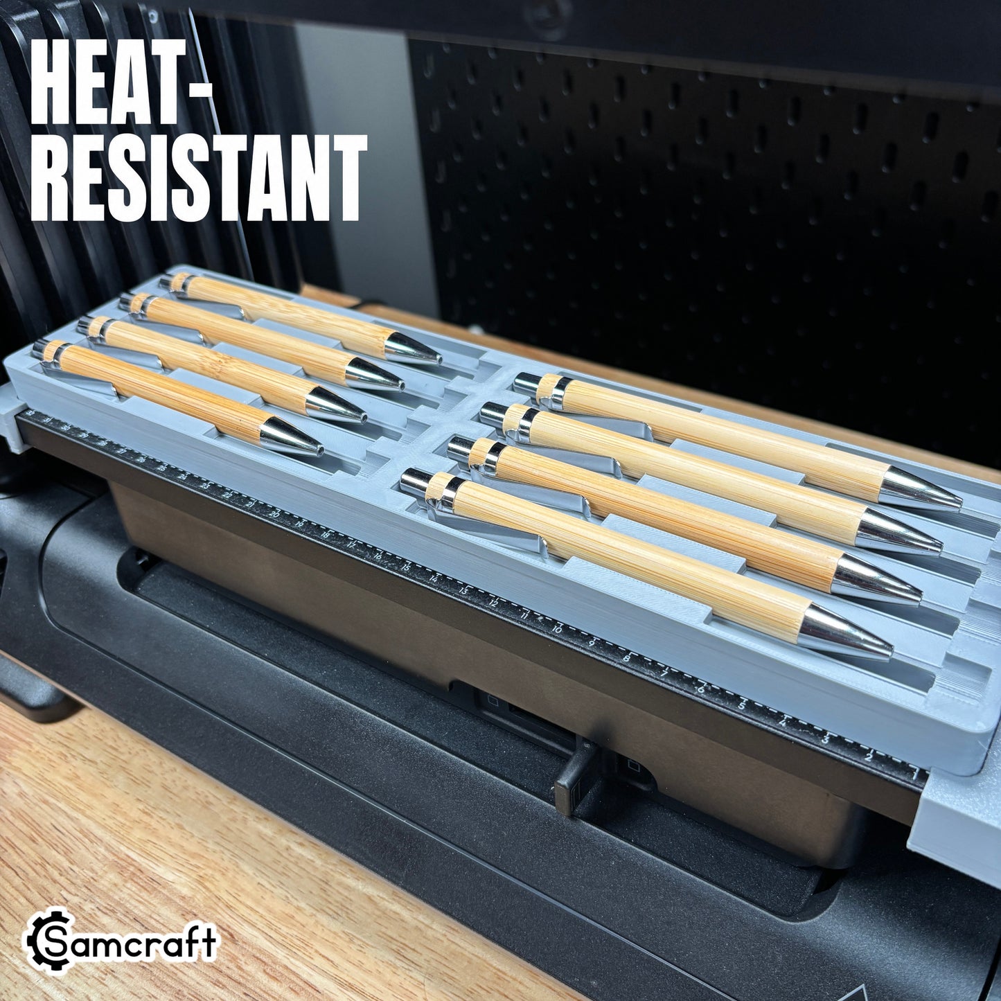 Heat-resistant Samcraft Universal Pen Jig holding eight bamboo pens with chrome tips in a gray tray with built-in ruler on the eufyMake E1 UV printer.
