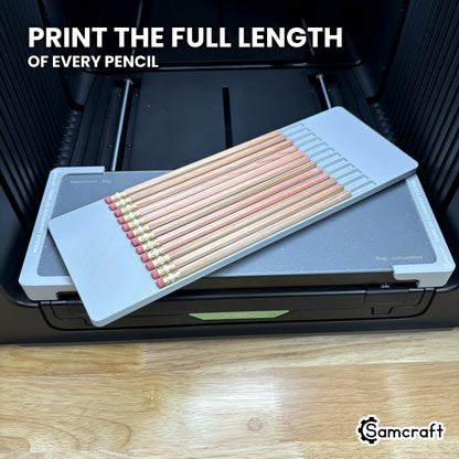 Angled view of twelve hexagon pencils lying full length in the Samcraft xTool Omni jig, one flat facet turned up toward the print head.