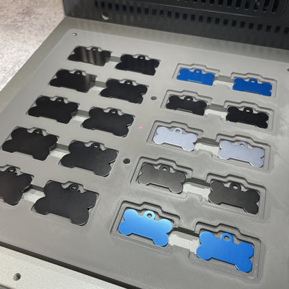 Samcraft bone pet tag jig on the xTool F2 Ultra bed, holding bone-shaped pet tags in black, silver and blue.