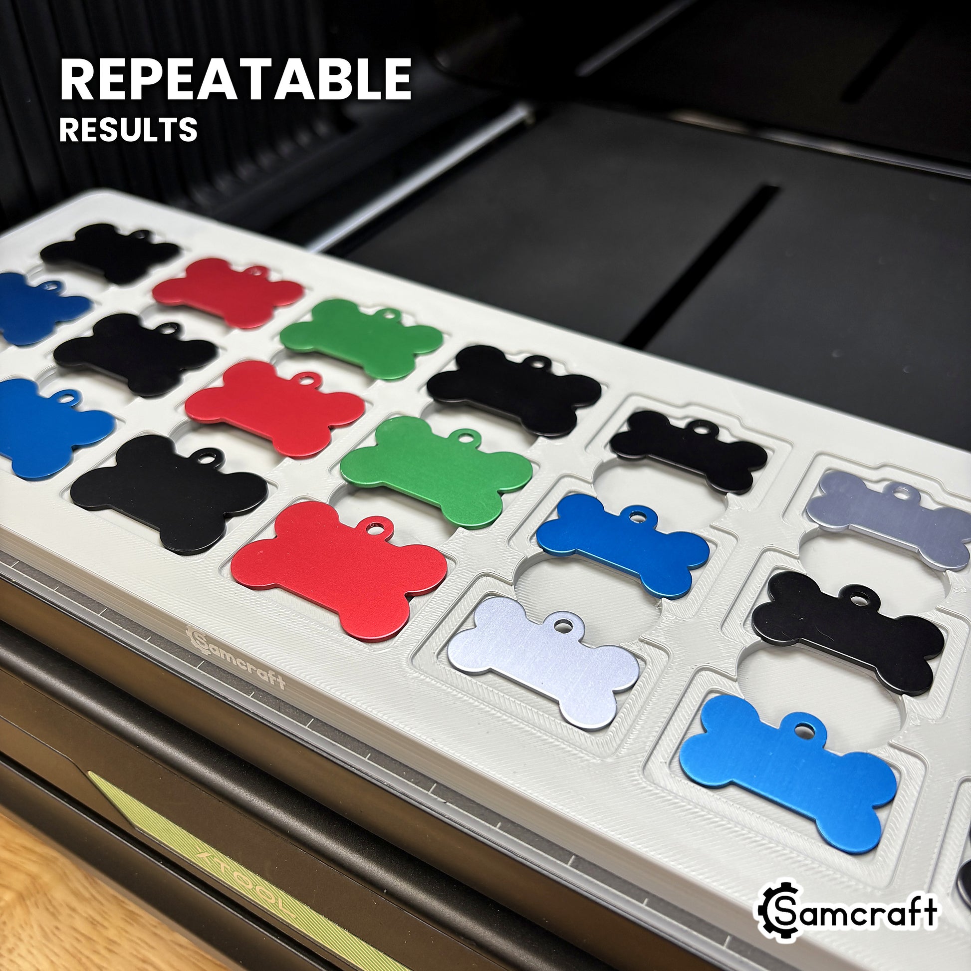 Angled view of the Samcraft bone pet tag jig full of colored aluminum tags on the xTool Omni printer bed, for repeatable print placement.