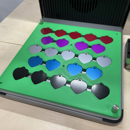Samcraft green heart pet tag jig in an xTool F1 Ultra laser bed, holding heart-shaped aluminium pet tags in several colours.