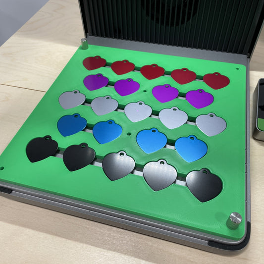 Samcraft green heart pet tag jig in an xTool F1 Ultra laser bed, holding heart-shaped aluminium pet tags in several colours.