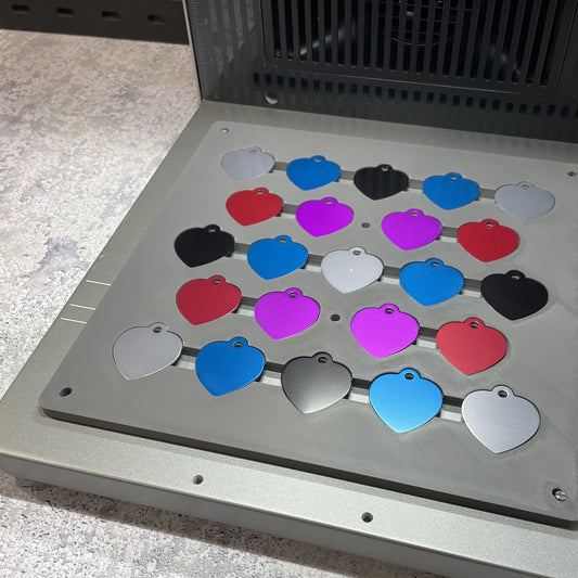 Samcraft heart pet tag jig on the xTool F2 Ultra bed, holding heart-shaped pet tags in many colours.
