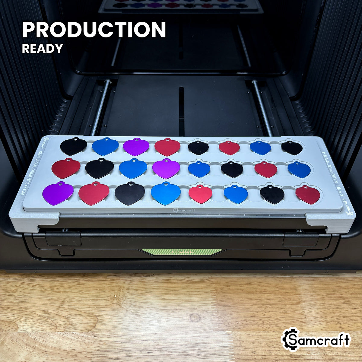 Samcraft heart pet tag jig holding 24 aluminum heart tags on the xTool Omni UV printer bed, set up for production runs.