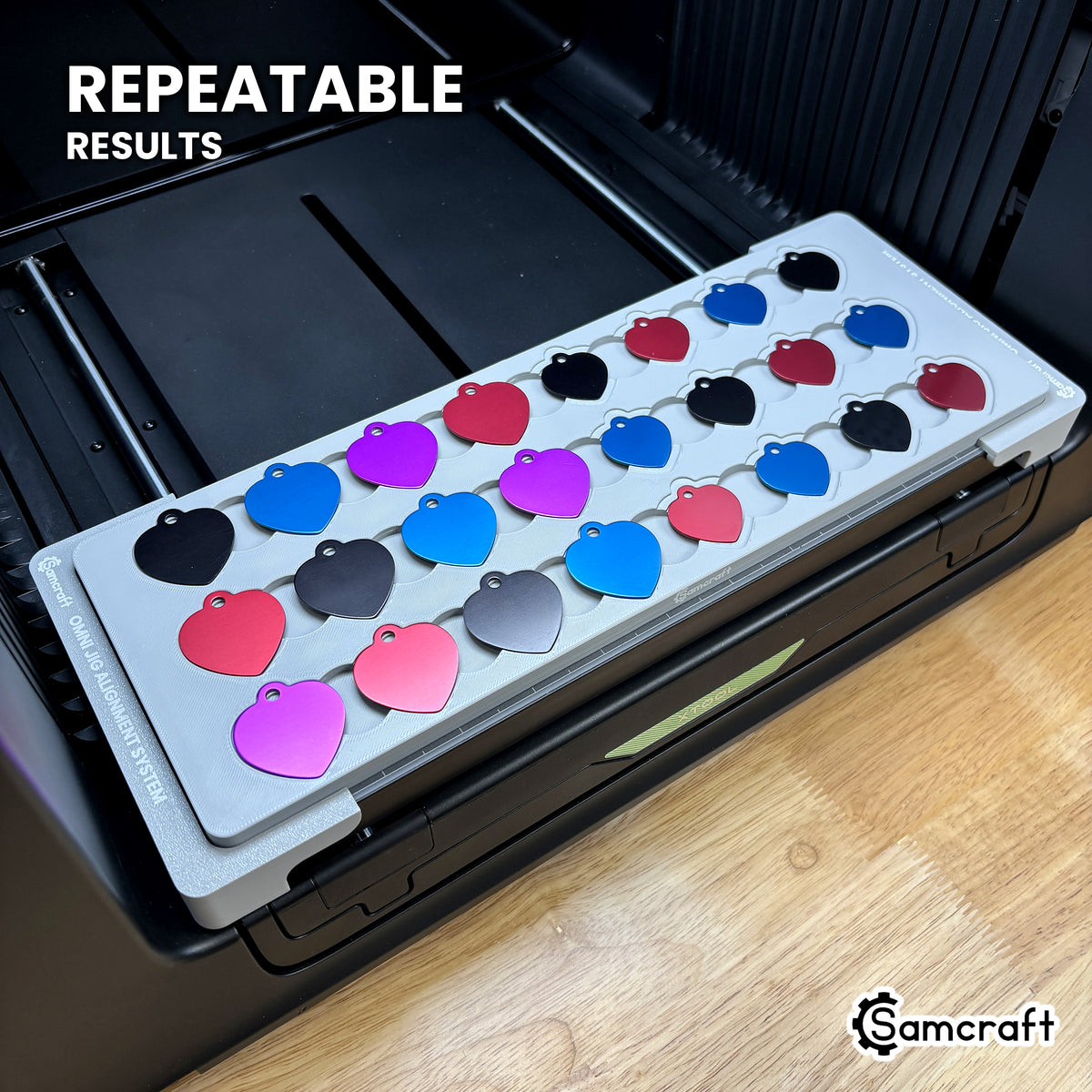 Angled view of the Samcraft heart pet tag jig full of colored aluminum tags on the xTool Omni printer bed, for repeatable print placement.