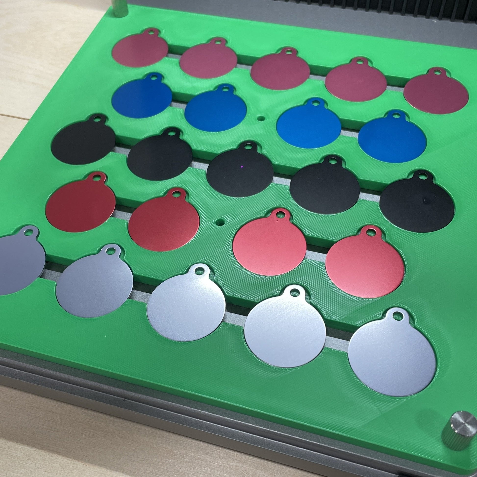 Samcraft green round pet tag jig in an xTool F1 Ultra laser bed, holding round aluminium pet tags in several colours.