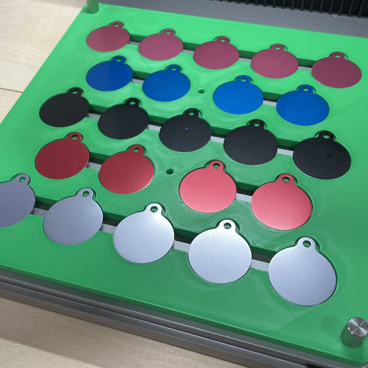 Samcraft green round pet tag jig in an xTool F1 Ultra laser bed, holding round aluminium pet tags in several colours.