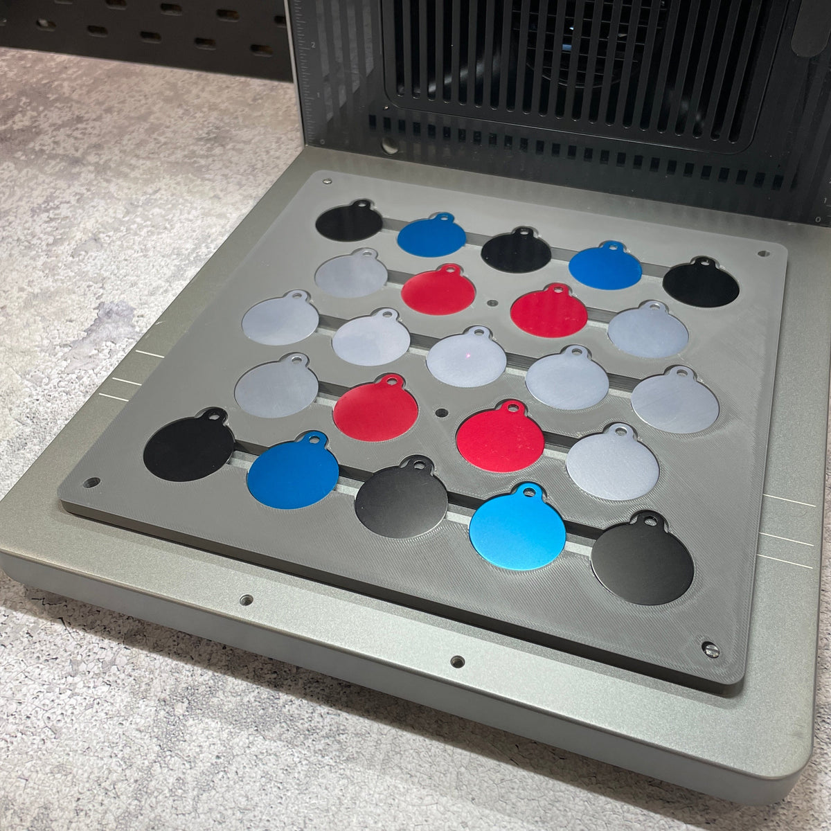 Samcraft round pet tag jig on the xTool F2 Ultra bed, holding round pet tags in many colours.