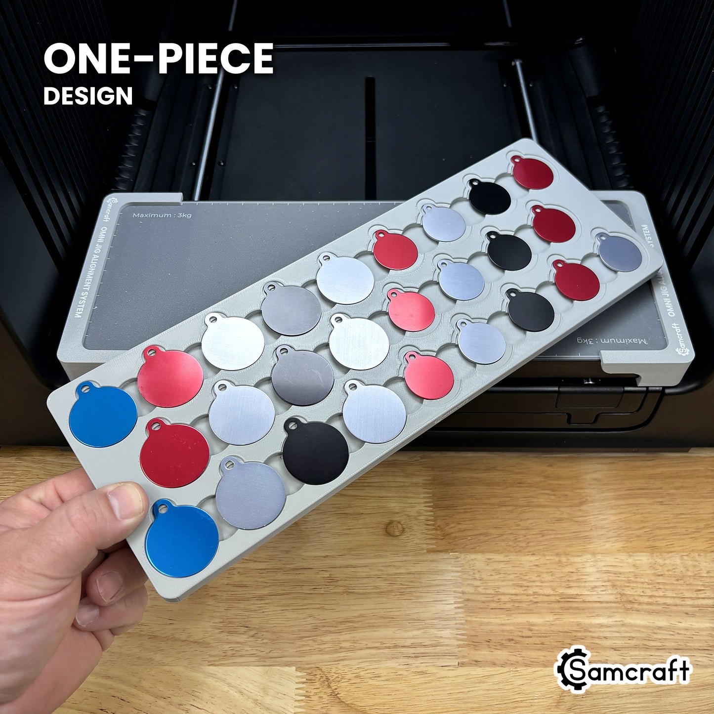 Hand holding the one-piece Samcraft round pet tag jig for the xTool Omni, colored aluminum round tags seated in a single molded gray tray.