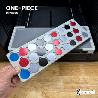 Hand holding the one-piece Samcraft round pet tag jig for the xTool Omni, colored aluminum round tags seated in a single molded gray tray.