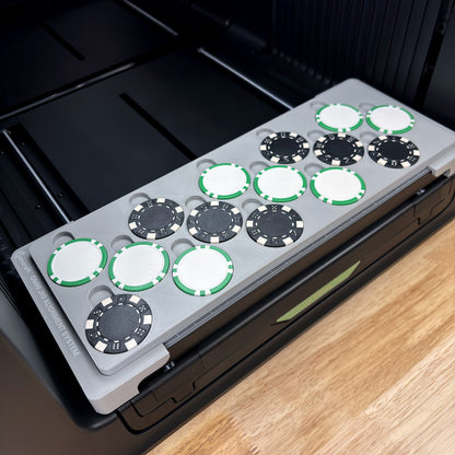 Samcraft poker chip jig on the bed of an xTool Omni UV printer, loaded with 15 poker chips in three staggered rows, black dice-stripe chips mixed with white chips edged in green stripes.