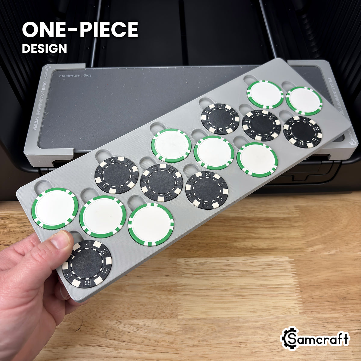 Hand holding the one-piece Samcraft poker chip jig for the xTool Omni, loaded with poker chips, in front of the printer bed.