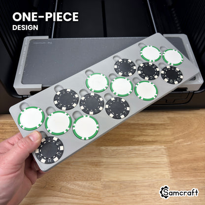 Hand holding the one-piece Samcraft poker chip jig for the xTool Omni, loaded with poker chips, in front of the printer bed.