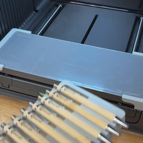 Video of the Samcraft universal 18 pen jig for the xTool Omni UV printer being loaded with bamboo pens and placed on the printer bed.