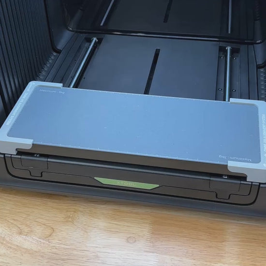 Video of the Samcraft flat metal keychain bottle opener jig for the xTool Omni UV printer being loaded and placed on the printer bed.