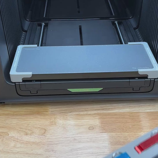 Video of the Samcraft keychain bottle opener jig for the xTool Omni UV printer being loaded with aluminum openers and placed on the printer bed.