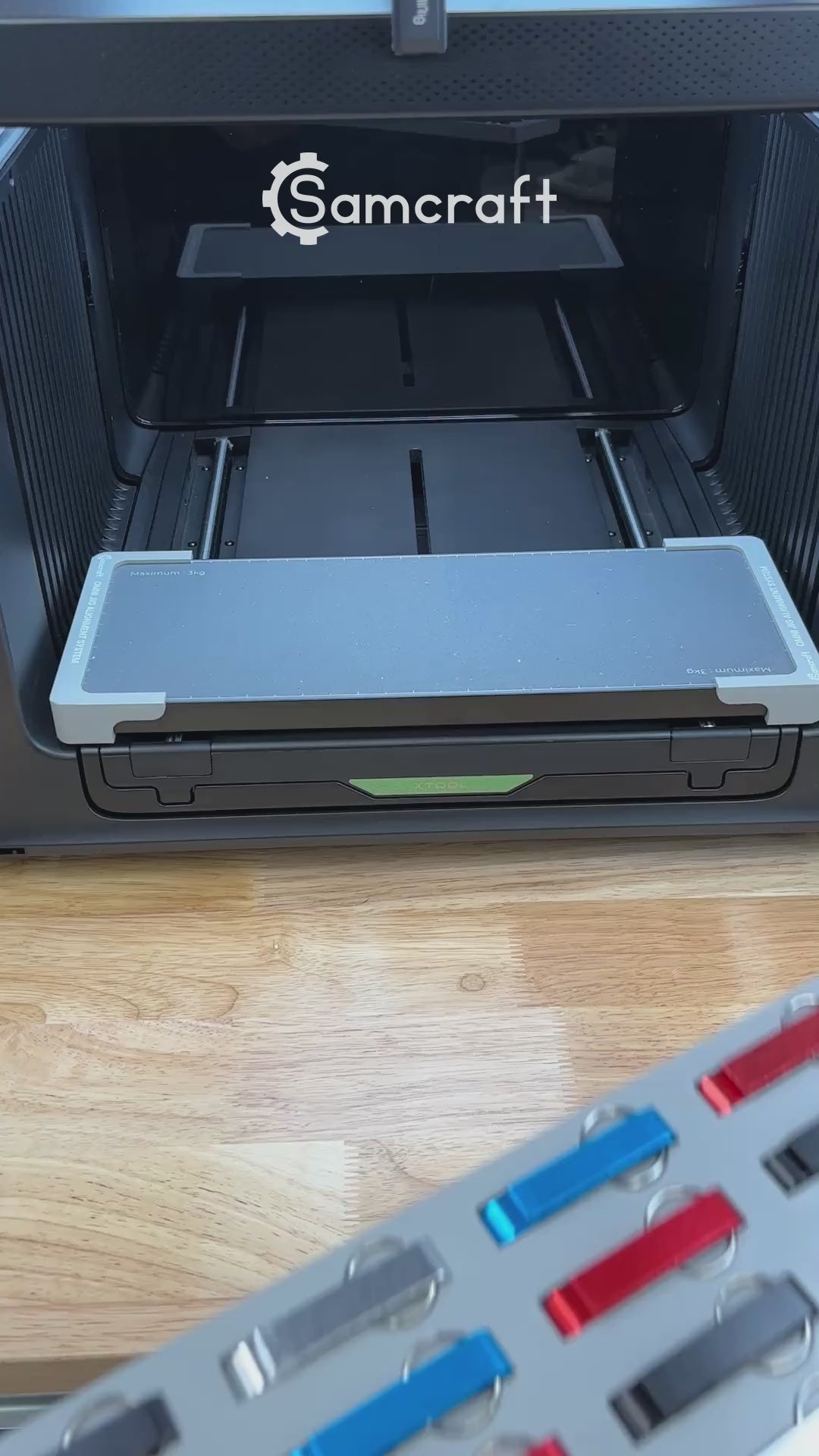Video of the Samcraft keychain bottle opener jig for the xTool Omni UV printer being loaded with aluminum openers and placed on the printer bed.