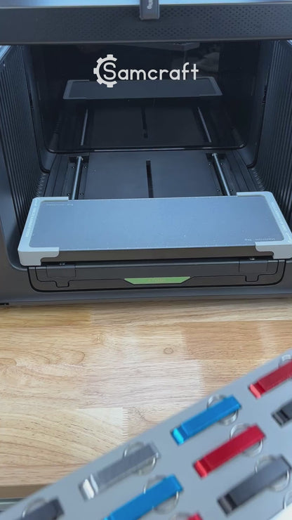 Video of the Samcraft keychain bottle opener jig for the xTool Omni UV printer being loaded with aluminum openers and placed on the printer bed.