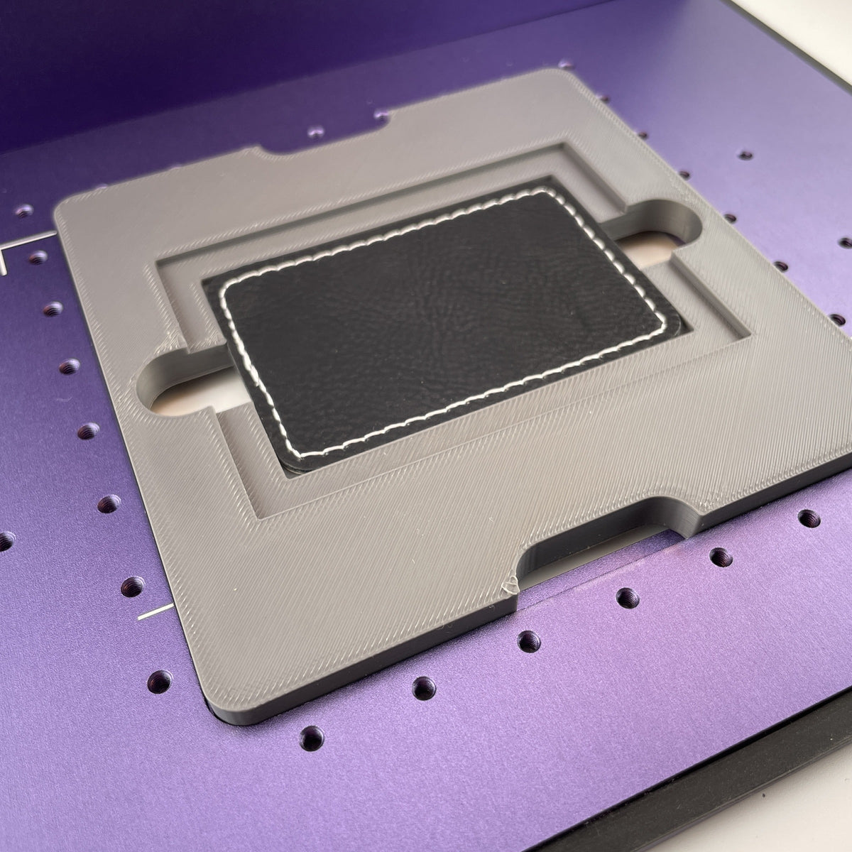 Samcraft rectangle patch jig on the purple bed of a WeCreat Lumos, holding a rectangular black leatherette patch.