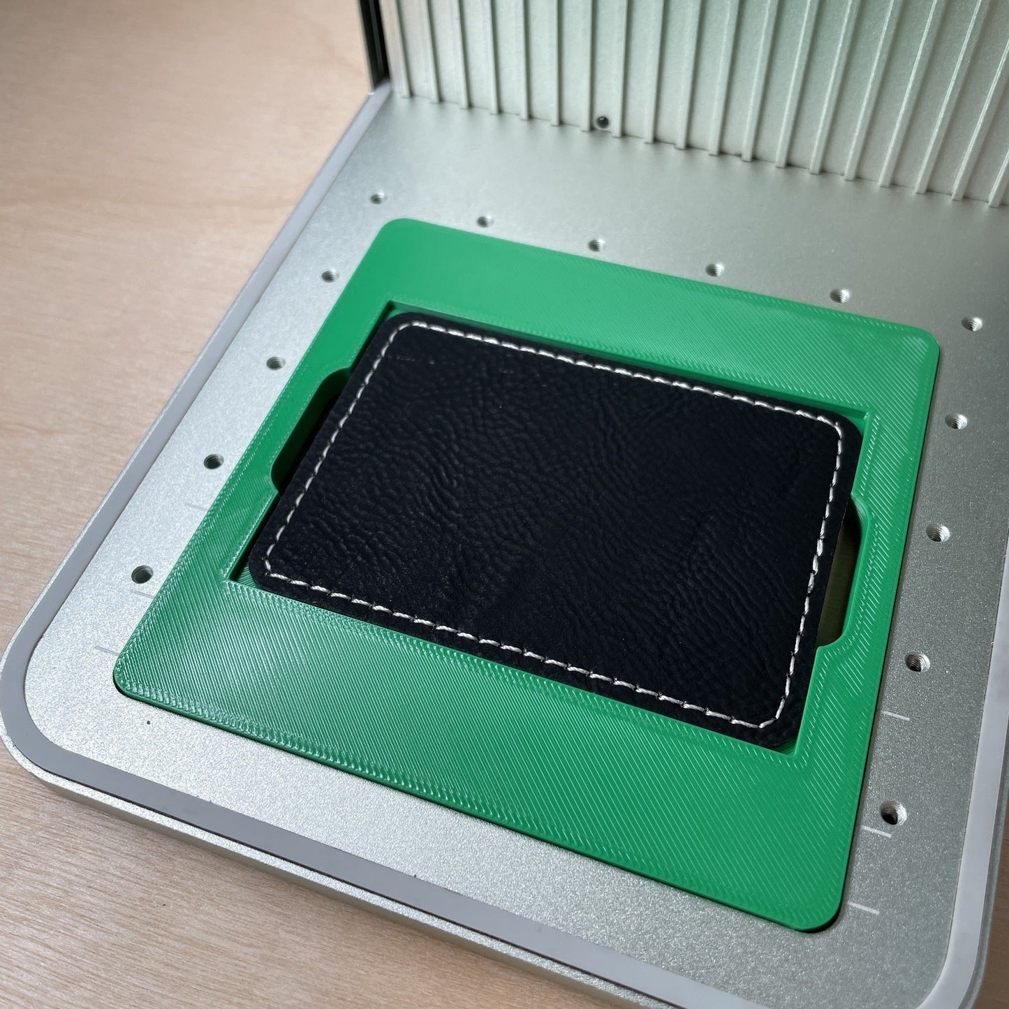 Samcraft rectangle patch jig in an xTool F1 laser bed, holding a black leatherette rectangle patch.