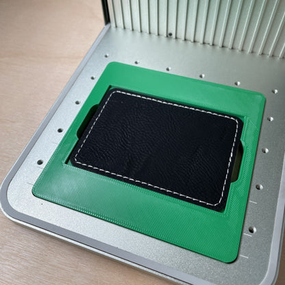 Samcraft rectangle patch jig in an xTool F1 laser bed, holding a black leatherette rectangle patch.