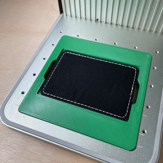 Samcraft rectangle patch jig in an xTool F1 laser bed, holding a black leatherette rectangle patch.