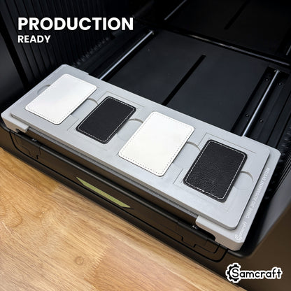Samcraft rectangle patch jig loaded with four leatherette patches on the xTool Omni UV printer bed, set up for production runs.