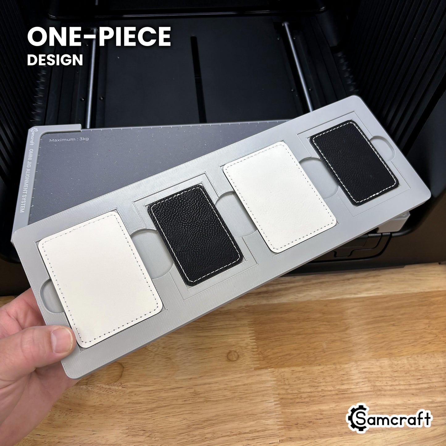 Hand holding the one-piece Samcraft rectangle patch jig for the xTool Omni, four patch pockets in a single molded tray.