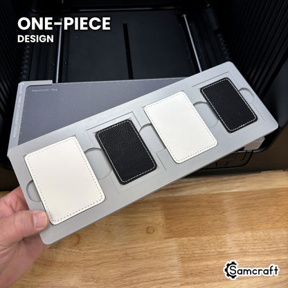 Hand holding the one-piece Samcraft rectangle patch jig for the xTool Omni, four patch pockets in a single molded tray.