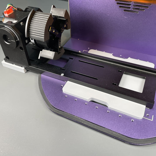 Samcraft rotary alignment jig on the purple bed of a WeCreat Lumos, positioning the rotary attachment on its rail.