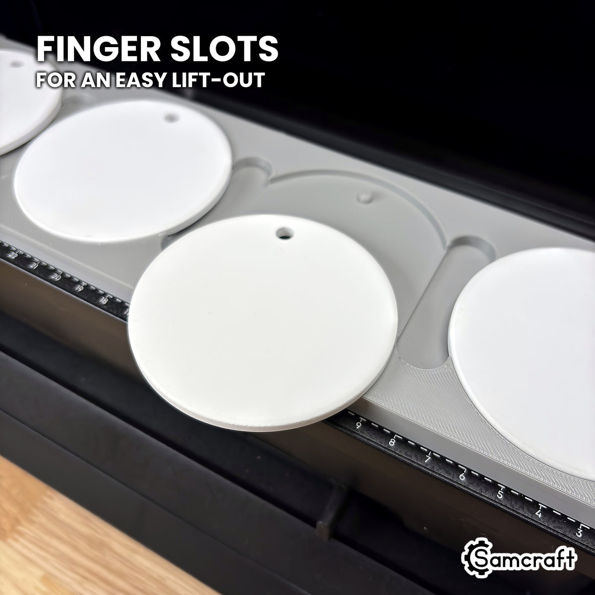 A white ceramic ornament tilted up out of its pocket in the Samcraft eufyMake E1 jig, showing the finger slots for an easy lift-out.
