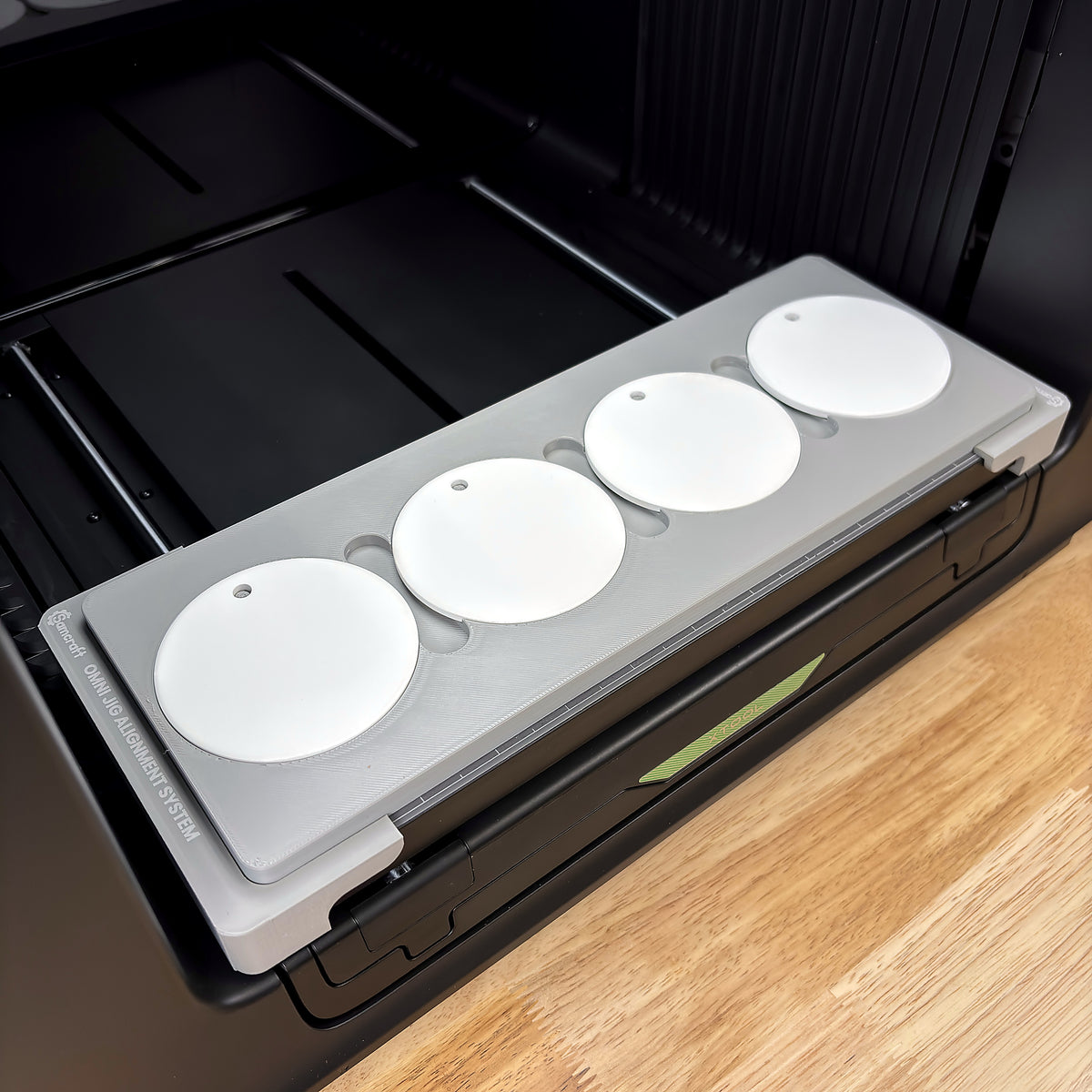Samcraft round ceramic ornament jig on the bed of an xTool Omni UV printer, holding four white round ceramic ornaments, seated on the Omni Jig Alignment System.