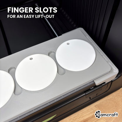 Close-up of the Samcraft round ceramic ornament jig for the xTool Omni showing the finger slots between the pockets for lifting each ornament out.