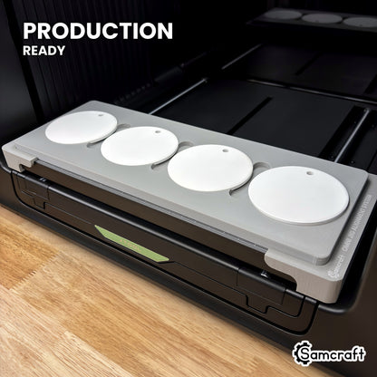 Samcraft round ceramic ornament jig holding four white ceramic ornaments on the xTool Omni UV printer bed, set up for production runs.